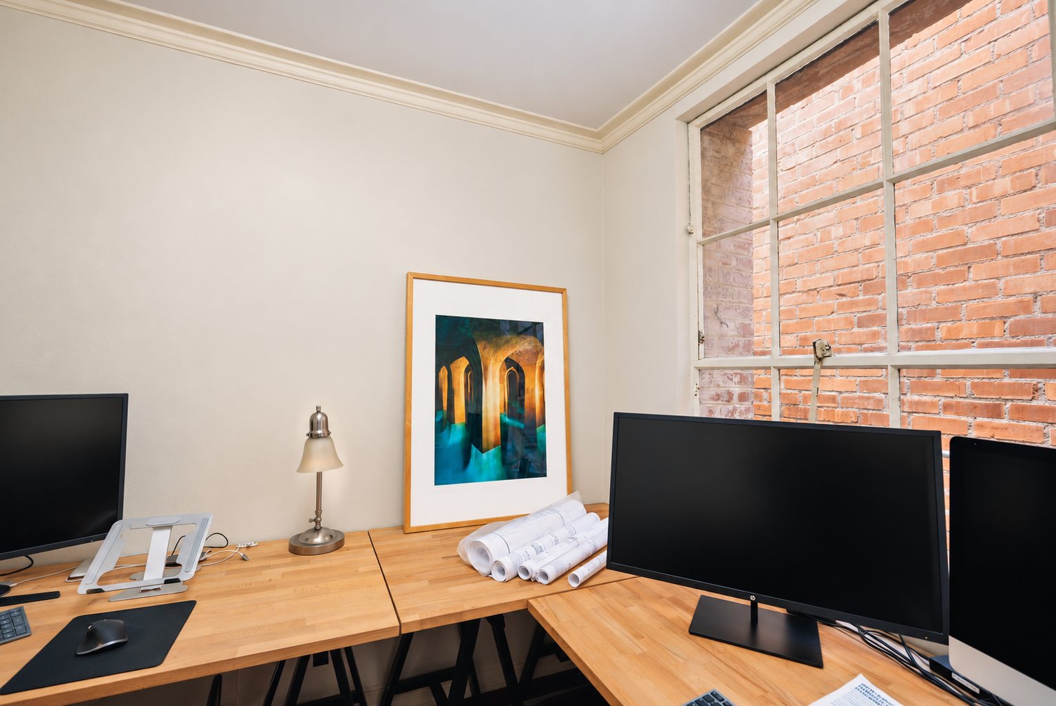 Corner of the office with framed art, desk lamp and window